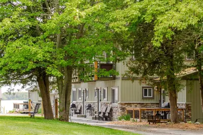 a building with a table and chairs and trees at Westlake Cottage - Milford Lodge in Wellington