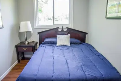 a bed with a blue comforter in a bedroom at Westlake Waupoos Cottage in Wellington