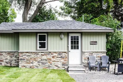 a small cottage with two chairs in a yard at Westlake Bloomfield Cottage in Wellington