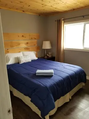 a bedroom with a bed with a blue comforter and a window at Westlake Cottage - Wellington Lodge in Wellington