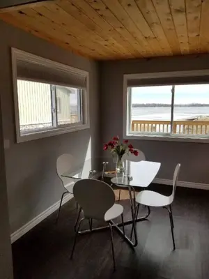 a dining room with a table and chairs and two windows at Westlake Cottage - Wellington Lodge in Wellington
