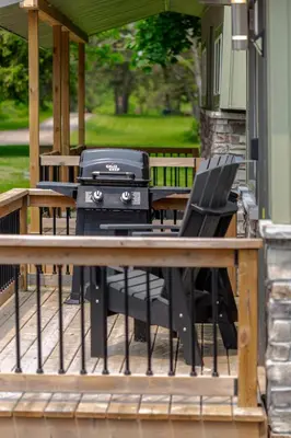a grill on a porch with chairs and tables at Westlake Cherry Valley Cottage in Wellington