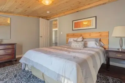 a bedroom with a large bed and a wooden ceiling at Westlake Consecon Cottage in Wellington