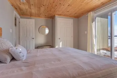 a bedroom with a large bed with a wooden ceiling at Westlake Consecon Cottage in Wellington
