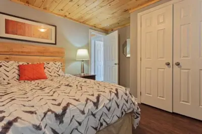 a bedroom with a large bed and a wooden ceiling at Westlake Consecon Cottage in Wellington