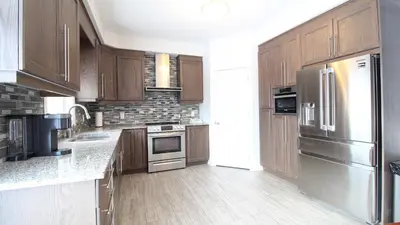 a kitchen with wooden cabinets and stainless steel appliances at Beautiful House Near Grand River & Kiwanis Park in Kitchener
