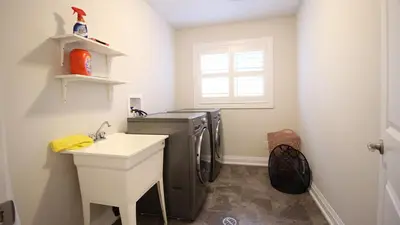 a laundry room with a sink and a washing machine at Beautiful House Near Grand River & Kiwanis Park in Kitchener