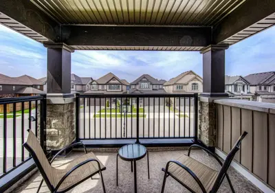 a balcony with chairs and a table with a view of houses at Beautiful House Near Grand River & Kiwanis Park in Kitchener