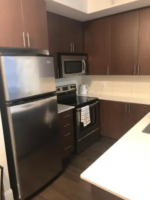 a kitchen with a stainless steel refrigerator and a microwave at Chic Toronto Blue Jays Getaway in Toronto