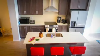 a kitchen with a sink and red chairs at Newly Built 3 plus 1 bedroom Ravine lot Townhouse, Brampton, Ontario in Brampton