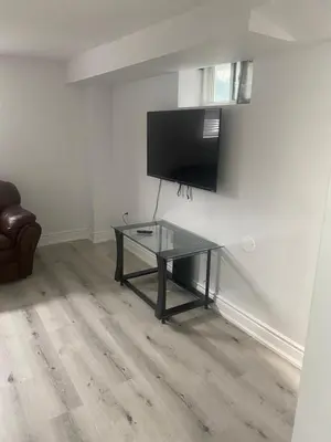 a living room with a glass table and a flat screen tv at 2 bedroom 2 bath separate basement unit in Cambridge