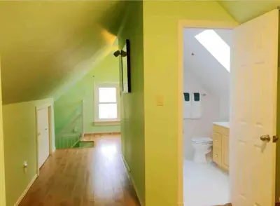 a bathroom with green walls and a toilet and a window at Cozy 1 bedroom 4 mins to falls in Niagara Falls