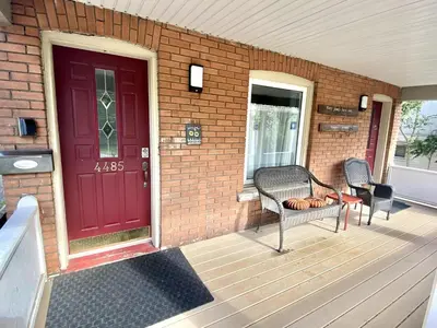 a porch with two chairs and a red door at Two bedrooms unit with jacuzzi in Niagara Falls