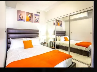 a bedroom with two beds with orange pillows at Exquisite Living Toronto in Toronto