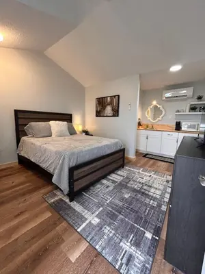 a bedroom with a large bed and a kitchen at Smokehouse Suites and Stay in Guelph