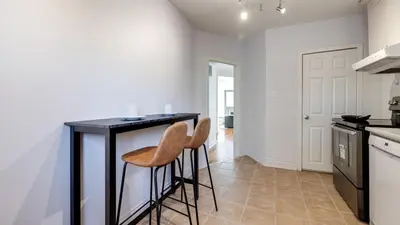 a kitchen with a black counter and two stools at Urban Oasis, 3-Bedroom Apartment at Prime Location in Toronto