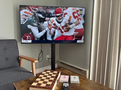 a flat screen tv in a living room with a football game at Waterfront Cottage Near Toronto Private Dock, Water Crafts, BBQ Wi-Fi - Sleeps 4 in Manvers