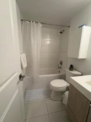 a white bathroom with a toilet and a shower at Sweetheart studio with city views in Toronto