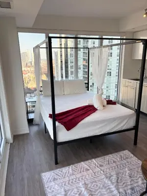 a bedroom with a canopy bed with a large window at Sweetheart studio with city views in Toronto