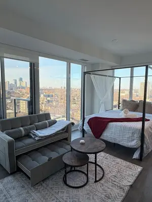a bedroom with a bed and a couch and windows at Sweetheart studio with city views in Toronto