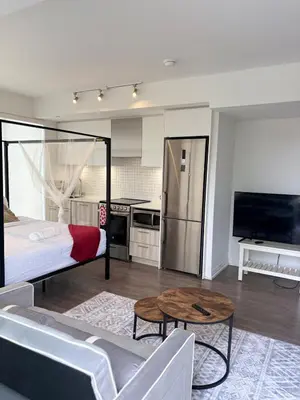 a room with a bed and a table and a kitchen at Sweetheart studio with city views in Toronto