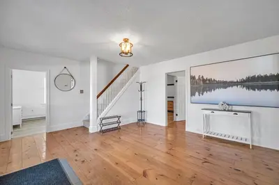 a living room with a staircase and a painting on the wall at Vintage 8BR Farmhouse With Hot Tub Spacious Yard in Port Colborne