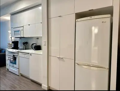 a kitchen with white cabinets and a refrigerator at KingBed & Bunkbed & Terrace in Toronto
