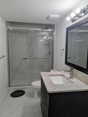 a bathroom with a shower with a toilet and a sink at Basement two Queen beds and one single with two full washrooms by YKF airport in Kitchener