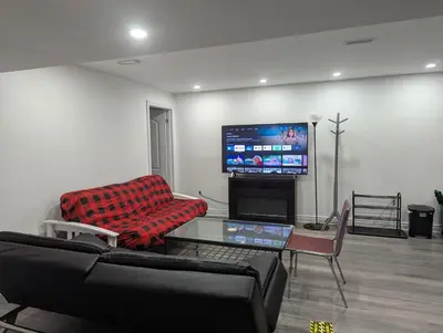 a living room with a couch and a flat screen tv at Basement two Queen beds and one single with two full washrooms by YKF airport in Kitchener