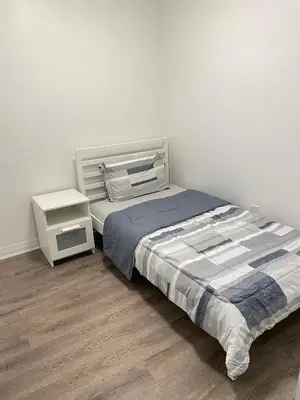 a white bedroom with a bed and a night stand at Executive Luxury Apartment in Oakville
