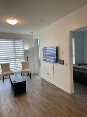 a living room with two chairs and a flat screen tv at Executive Luxury Apartment in Oakville