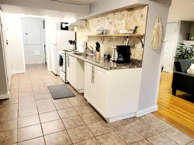 a kitchen with white cabinets and a tile floor at Charming Basement Studio Bathroom Full Kitchen in Toronto