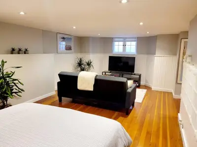 a living room with a couch and a flat screen tv at Charming Basement Studio Bathroom Full Kitchen in Toronto