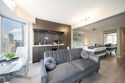 a living room with a couch and a bedroom at Discounted Elegant Yorkville Suite in Toronto