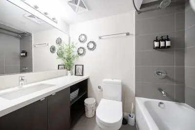 a bathroom with a toilet and a sink and a mirror at Discounted Elegant Yorkville Suite in Toronto