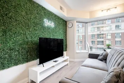 a living room with a tv and a green wall at Discounted Elegant Yorkville Suite in Toronto