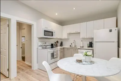 a white kitchen with a table and white appliances at Casa Leslieville - 2BR Suite with LRG Patio in Toronto