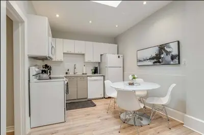 a kitchen with white appliances and a table and chairs at Casa Leslieville - 2BR Suite with LRG Patio in Toronto