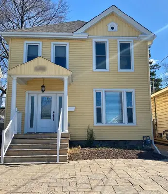 a yellow house with a front porch and stairs at Cozy Suite-Walk to the Falls in Niagara Falls