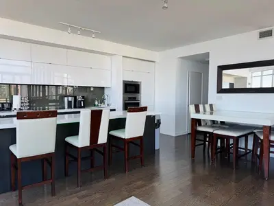 a kitchen with white cabinets and a table and chairs at Two Storey Penthouse with 2 Parkings and Lake & City Views in Toronto
