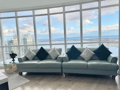 a living room with a couch in front of a large window at Two Storey Penthouse with 2 Parkings and Lake & City Views in Toronto