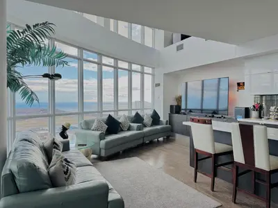a living room with a couch and a kitchen with windows at Two Storey Penthouse with 2 Parkings and Lake & City Views in Toronto