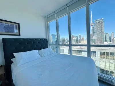 a bedroom with a bed with a view of the city at Two Storey Penthouse with 2 Parkings and Lake & City Views in Toronto