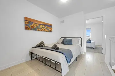 a white bedroom with a bed and a painting on the wall at Stylish 4-Bed Home with Backyard in Prime Location in Burlington
