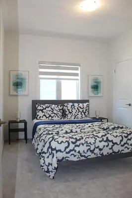 a bedroom with a large bed with a white and blue blanket at West Oak, Detached New Modern House In South Barrie - Built H plus ME Technology in Barrie