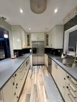 a kitchen with white cabinets and a stainless steel refrigerator at Chapman in Toronto
