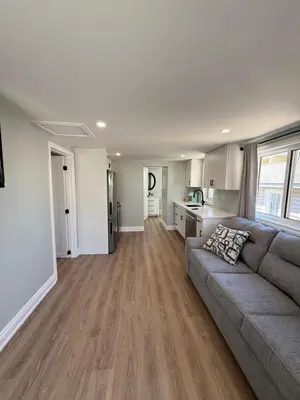 a living room with a couch and a kitchen at ORS Beach Corporation Wasaga Beach Cottage in Wasaga Beach