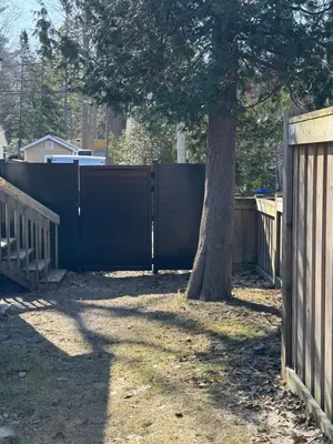 a fence next to a tree next to a tree at ORS Beach Corporation Wasaga Beach Cottage in Wasaga Beach