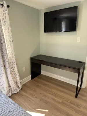 a bedroom with a desk with a television on the wall at ORS Beach Corporation Wasaga Beach Cottage in Wasaga Beach