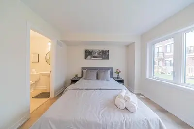 a white bedroom with a large bed with two white slippers at Entire home in Oakville, Canada in Oakville